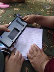 Image of two women's hands, holding a phone and a notebook