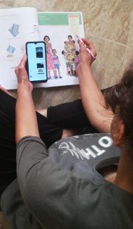 Image from above of a participant looking at her phone and her notebook, full of lessons and illustrations