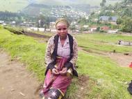 Zawadi N. standing in her village.