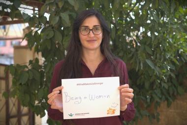 Khalida Lazgreen poses with a "What Makes Me Stronger" placard