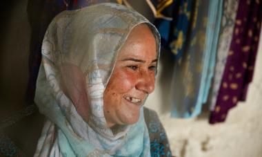 Shireen, a graduate of the Women for Women International program in Iraq, smiles facing off to the lower-right hand corner