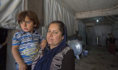 A refugee holds her child in a tent in the Khanke refugee camp in KRI.