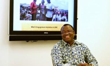 man in glasses sitting in front of tv screen