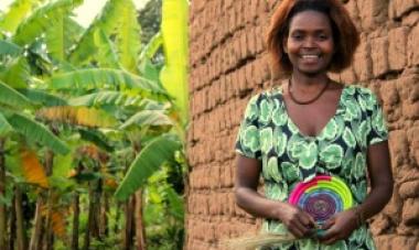 woman smiling in green patterned dress holding a handmade bowl